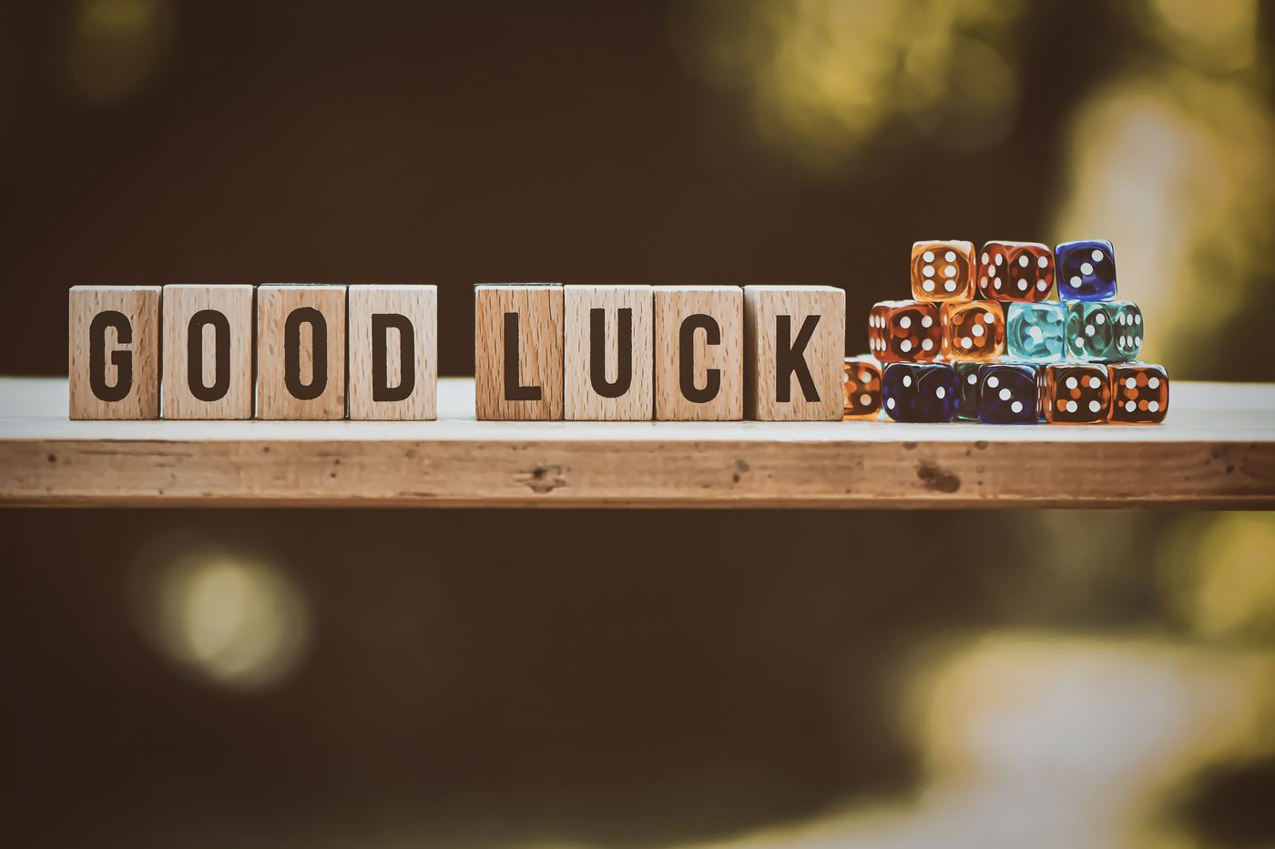 Wooden blocks spelling GOOD LUCK next to a stack of dice