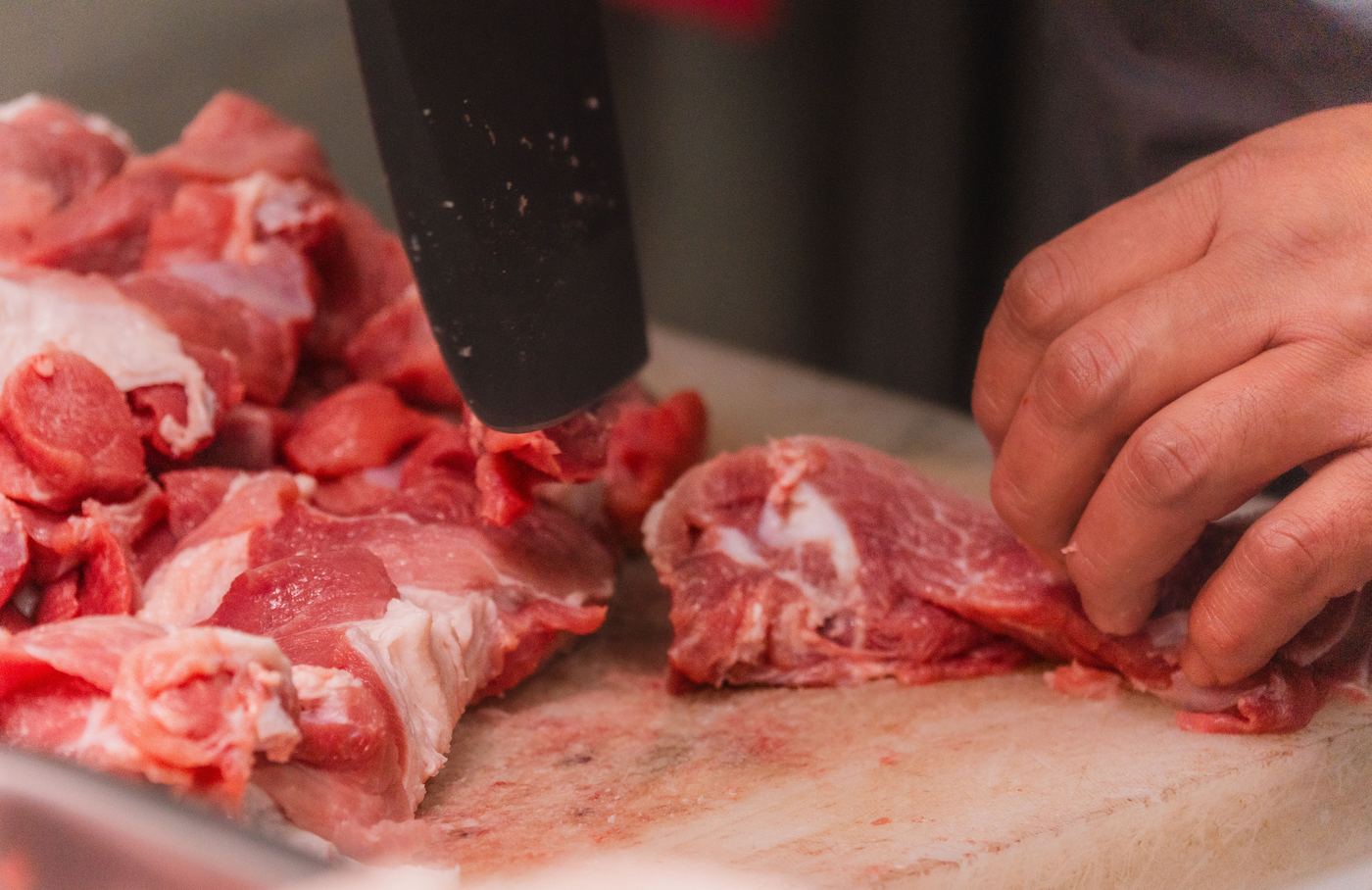 Hands trimming raw venison on a cutting board