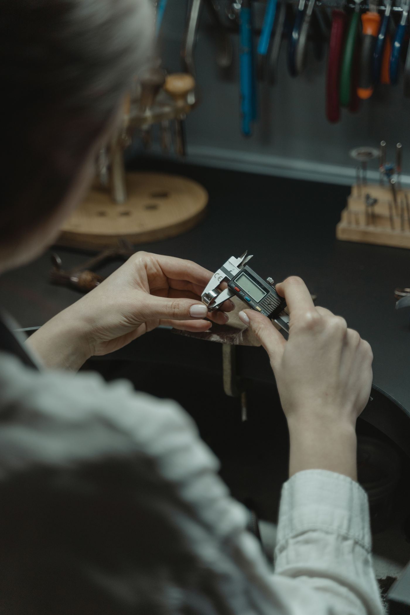 A reloader measuring a case with a digital caliper at the bench